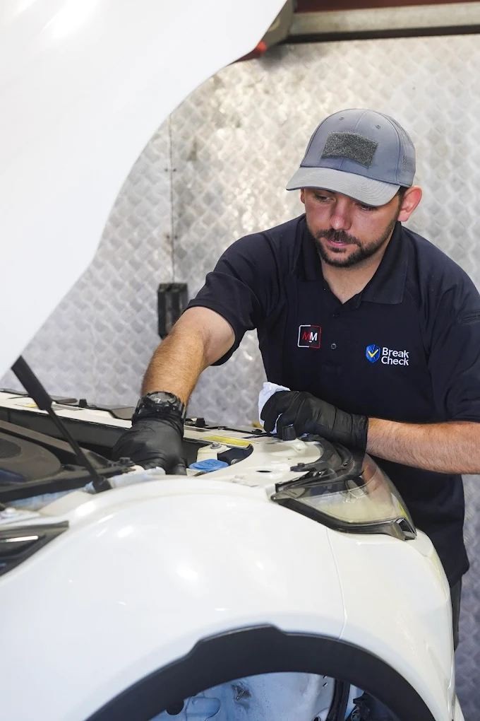 Break Check technician working in the engine bay of a white car